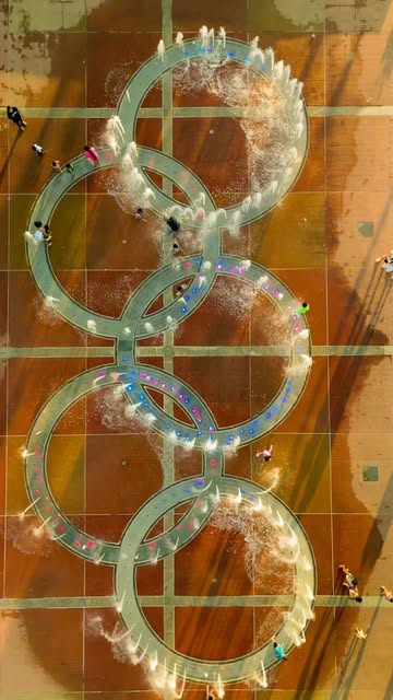 Aerial photo of people moving through circular fountains